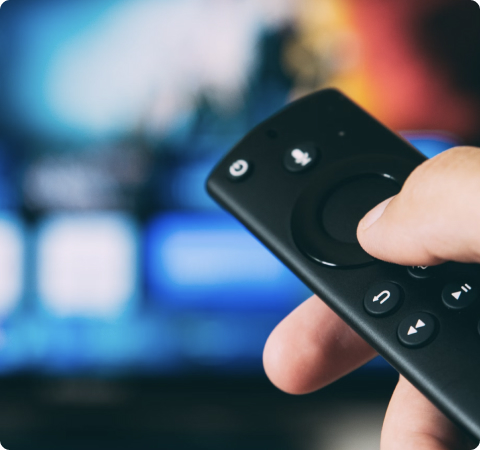 Photo of a hand holding a TV remote control.