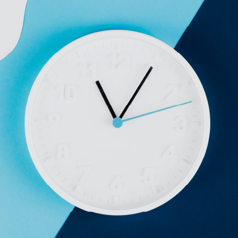 Minimalist white clock with blue and black hands showing the time